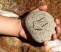 a hand holding a rock with a smiley face drawn on it
